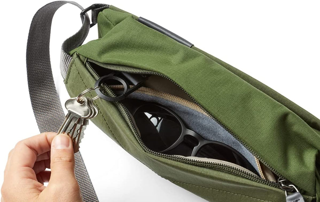 green sling bag unzipped showing key holder