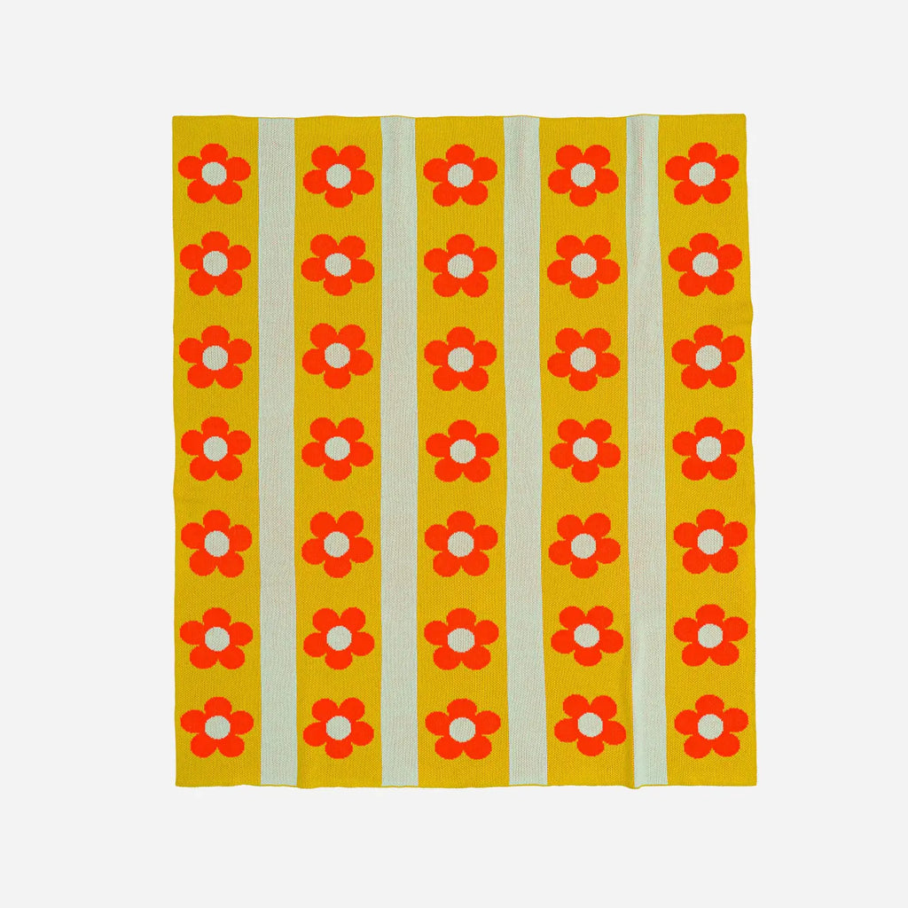 Yellow knit throw with red floral patterns on a white background