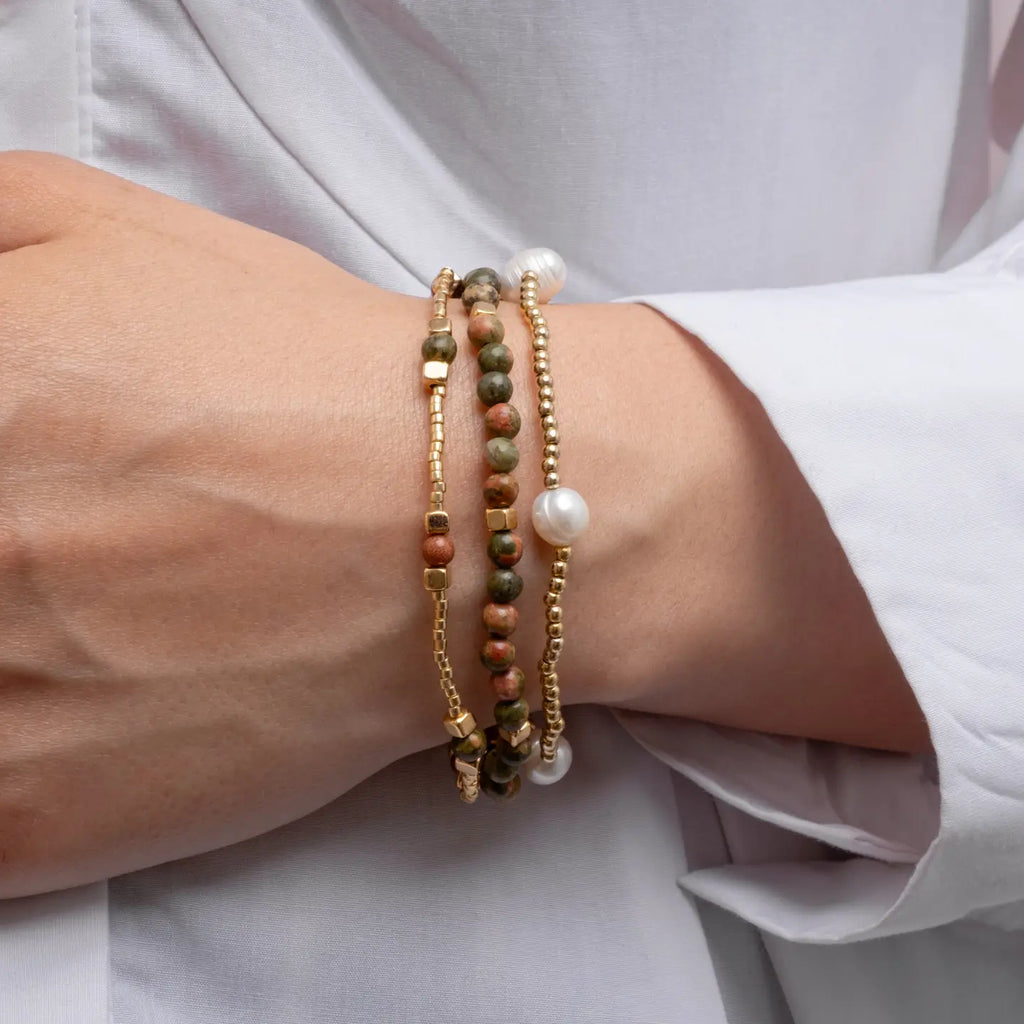 Close-up of a wrist wearing multiple beaded bracelets on a light background