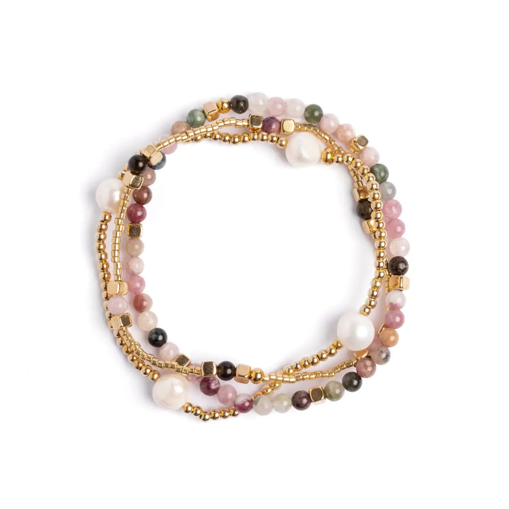 Stack of multicolored beaded, pearl and gold bracelets on a white background