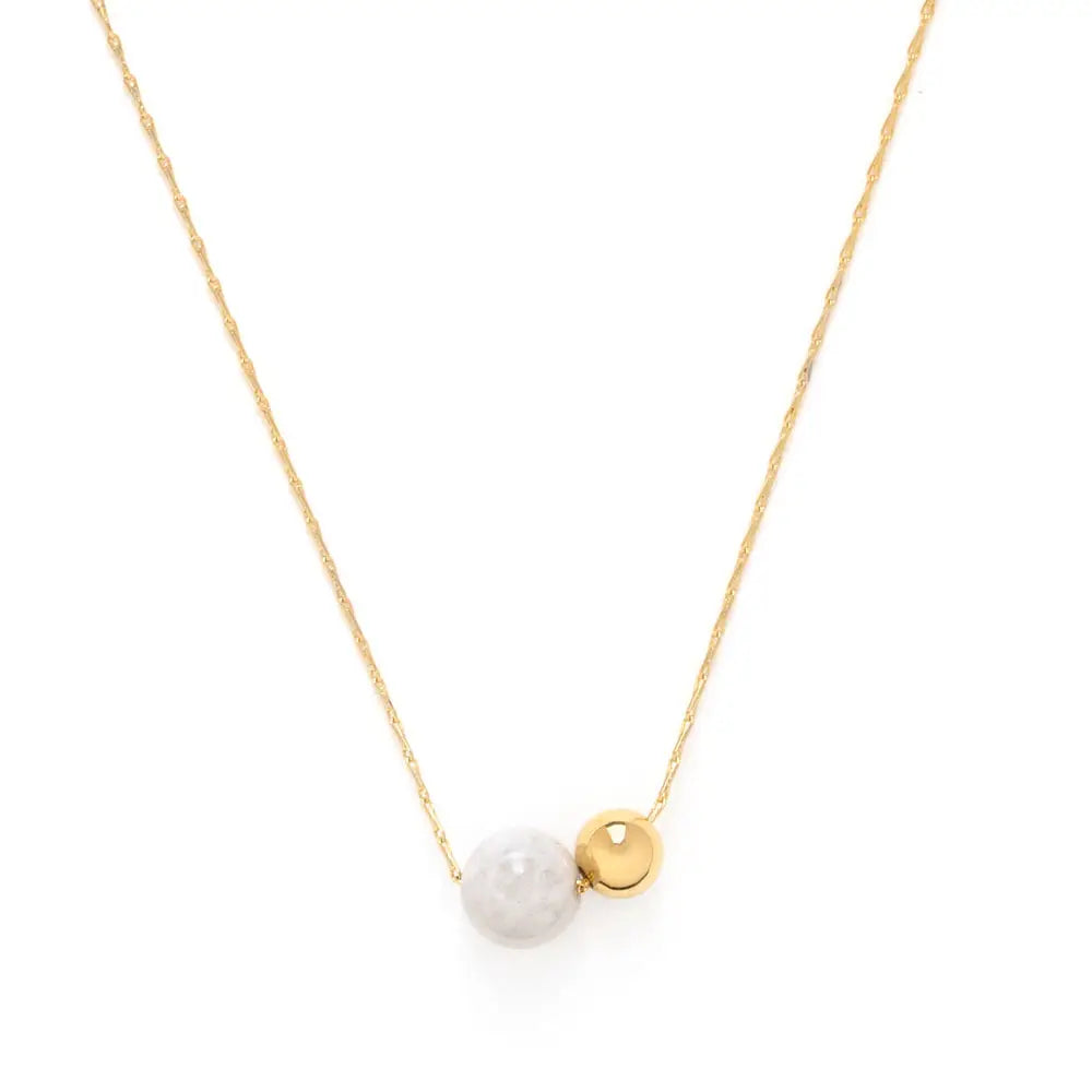 Gold necklace with a moonstone and gold bead pendant on a white background