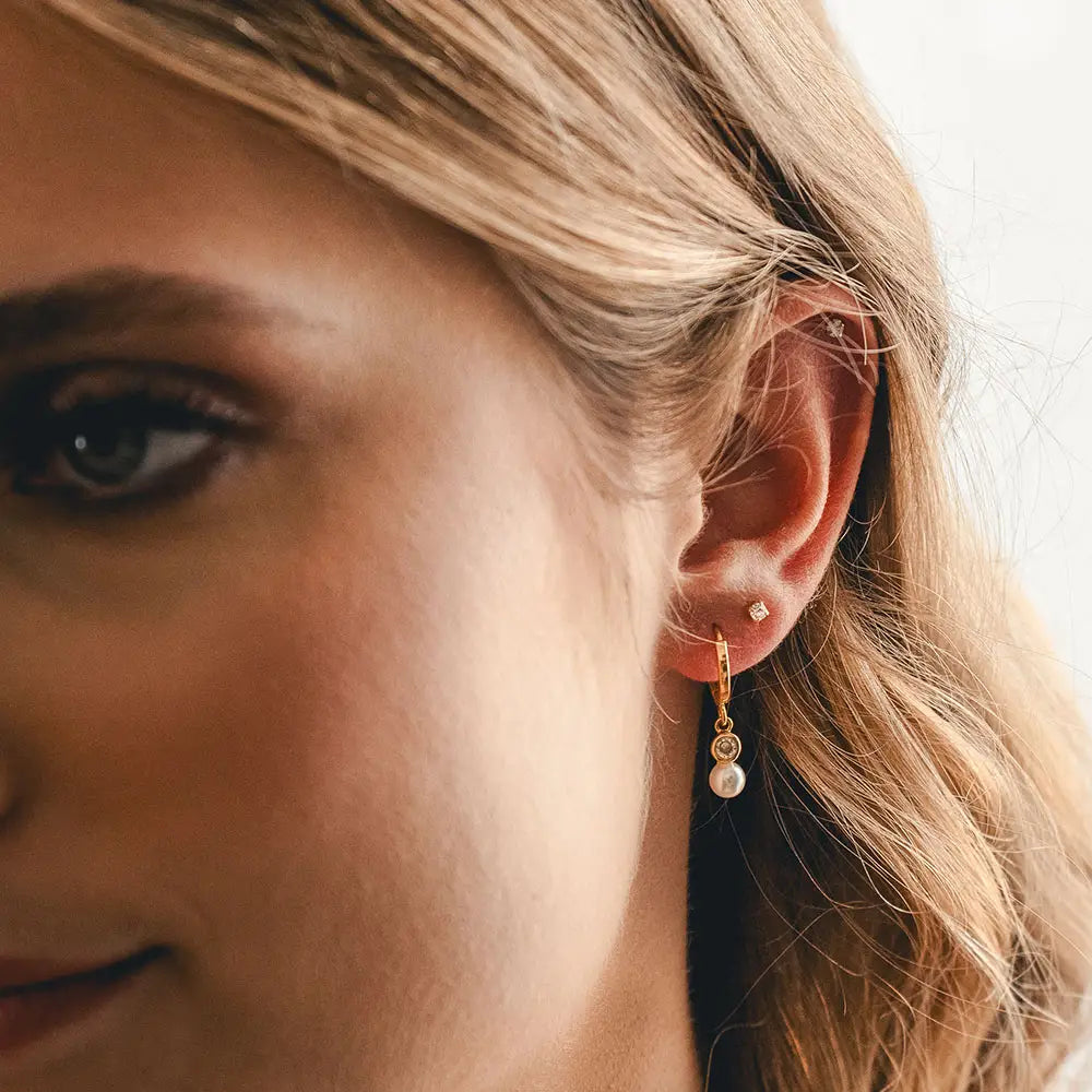 Close-up of a woman wearing pearl earrings with a blurred background