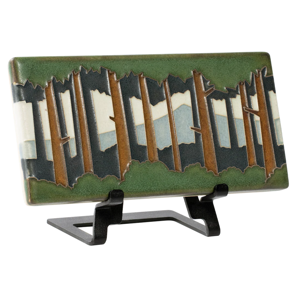 Decorative tile with a forest design on a stand against a white background