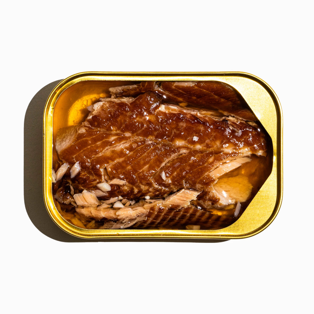Open tin of rainbow trout on a white background