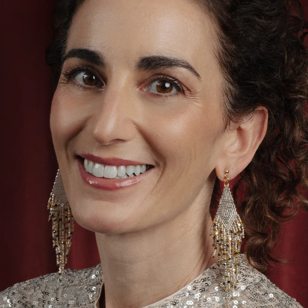 Woman wearing sparkling earrings with a blurred red background
