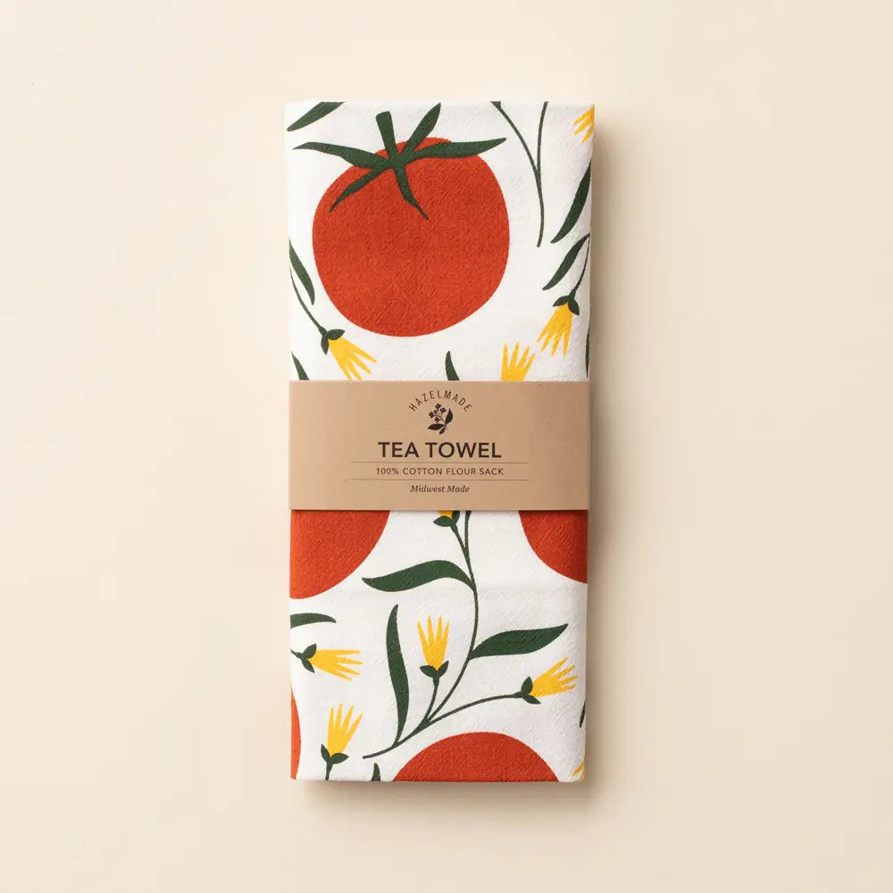 Tea towel with tomato and leaf design in packaging on a beige background
