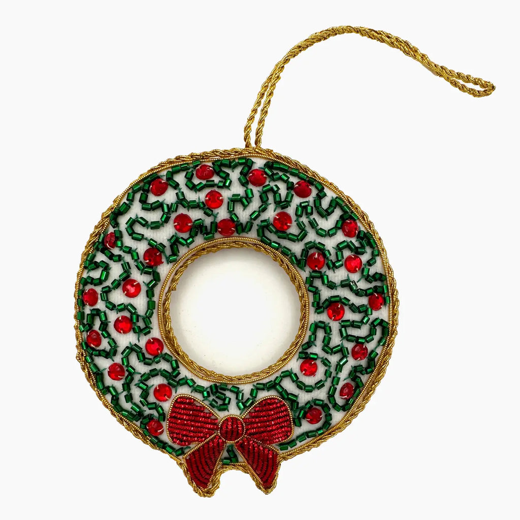 Decorative Christmas wreath ornament with red berries and a bow on a white background