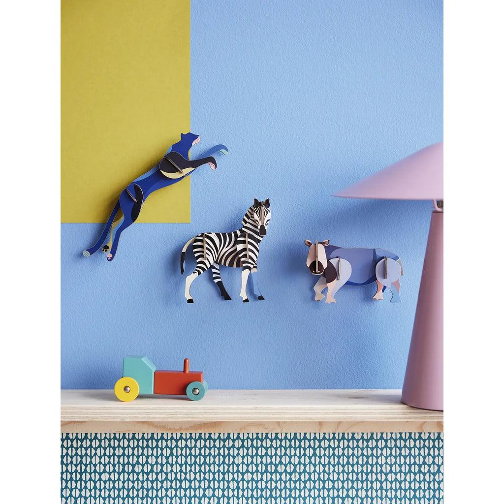 Colorful animal wall hooks on a blue and yellow wall with a lamp and toy car.