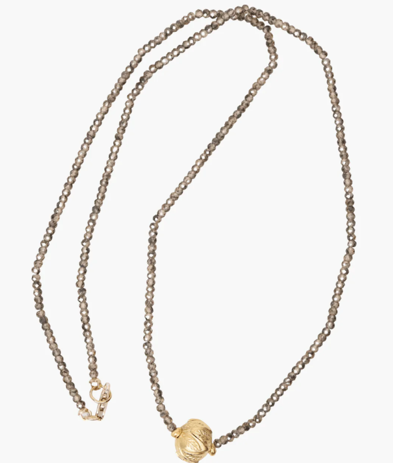 Necklace of zircon beads with a gold bead on a white background
