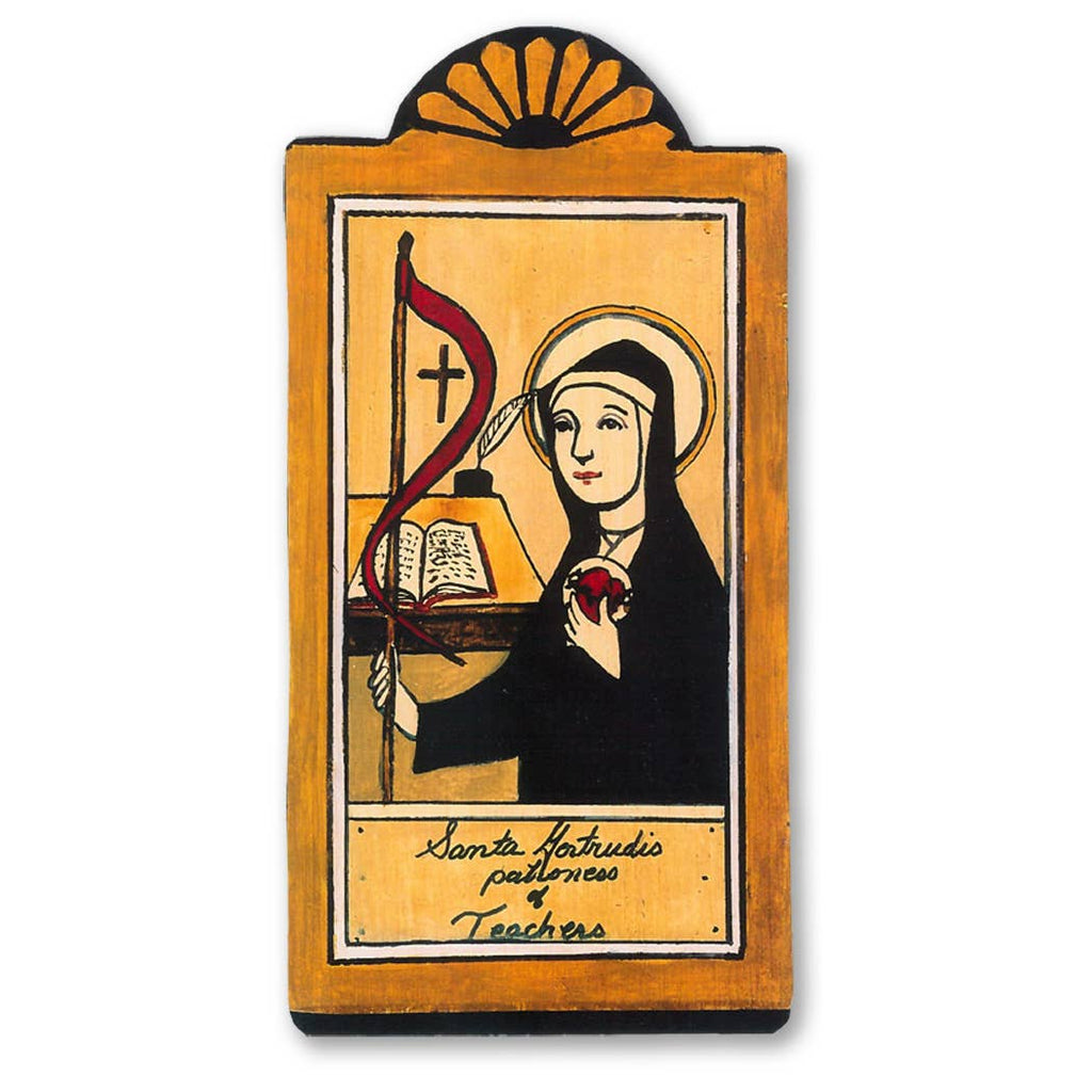 A rectangular wooden pocket saint retablo featuring a black and white illustration of St. Gertrudis, a patroness of teachers and students, holding a book and a staff, with a gold-colored halo and the text 'Sancta Gertrudis Patroness Teachers'.