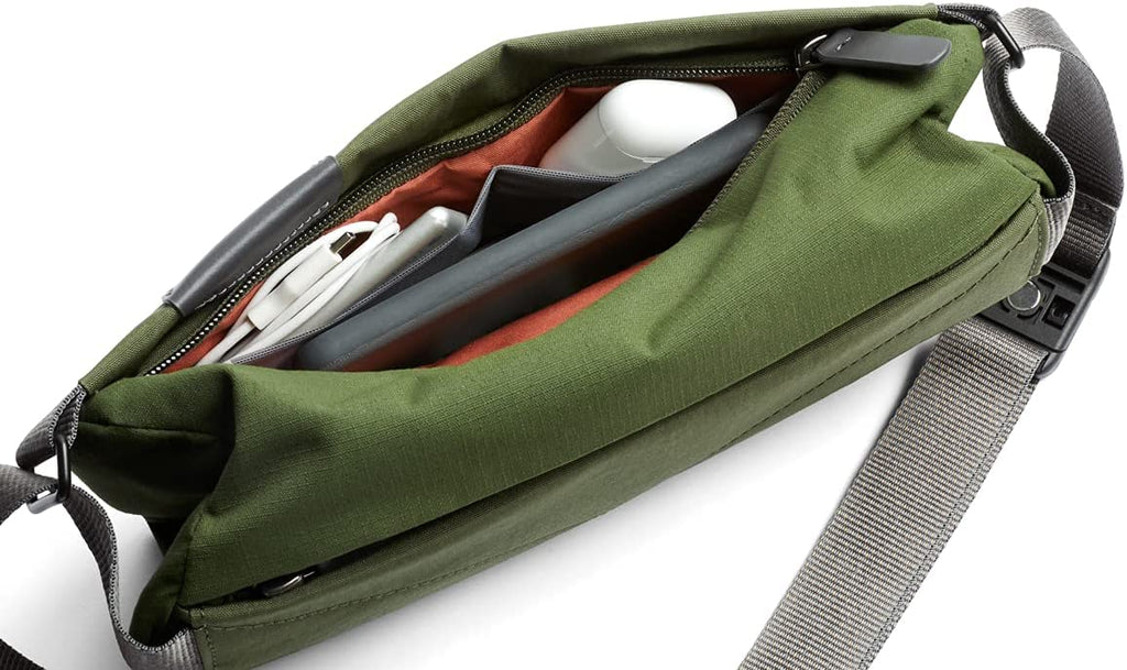 green mini sling bag unzipped with electronics packed inside